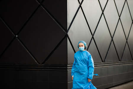 Female doctor or nurse in medical mask and blue surgical cap looking at youの写真素材