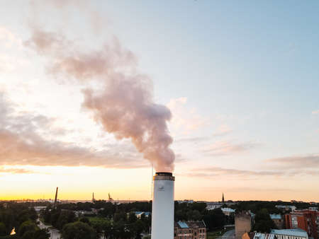 Large white pipe emits a lot of smoke causing greenhouse effect and global warming climate changeの写真素材