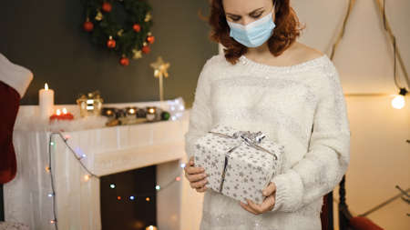 Sad young woman in surgical mask feeling down with white gift boxの写真素材