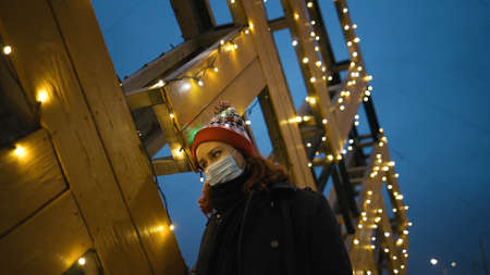 Exhausted young woman in protective mask feels down during xmas lockdown