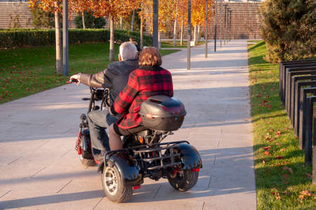 Couple of tourists on small rental electric three wheel scooterの写真素材