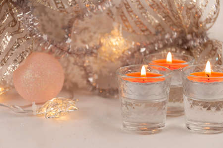 Three burning candles, a Christmas ball, glowing stars and festive decorationsの写真素材