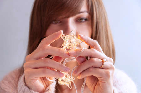 On the eve of Christmas. The girl holds glowing fairy lights.の写真素材