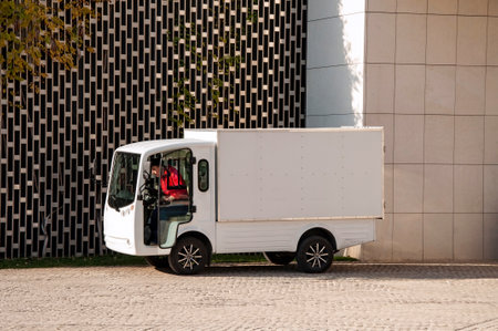 electric truck with driver in the cab stands near the wall and is chargedのeditorial素材