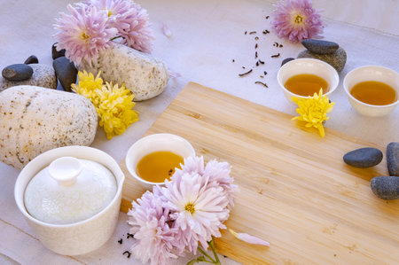 Chinese white tea cups on a bamboo board, beautiful white porcelain gaiwan zhong, flowers and stonesの写真素材