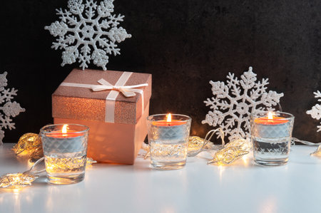 Golden rose gift box with shiny bow for present, candles, snowflakes for Christmas celebratingの写真素材