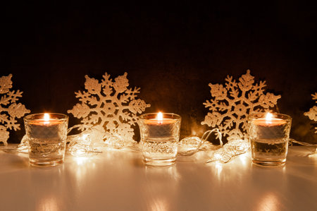 Composition of three burning candles, snowflakes and fairy lights in form of starsの写真素材