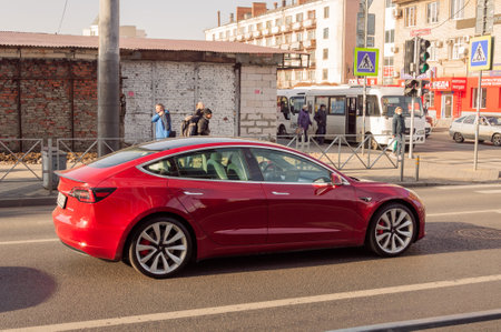 Red Tesla Car Model 3 on the city road in a sunny dayのeditorial素材