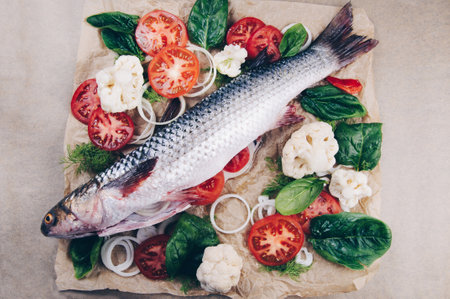 Fresh raw whole mullet fish on parchment paper before bakingの写真素材