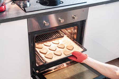 close-up partial view of person putting cookies into oven