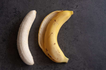 Healthy food. Ripe banana without peel on a grey background.の写真素材
