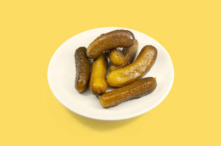 Pickles. White plate of pickled homemade cucumbers on yellow background.の写真素材