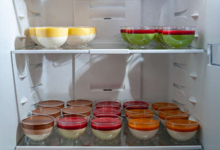Variety of sweet tasty desserts in plastic jars in the frige, selective focus. Delicious panna cotta with raspberries.の写真素材