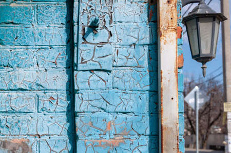 Blue cracked paint on a brick wall. Texture of the old cracked paint. Rusty metal. Old street latern.