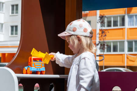 Girl Playing With Toy Outdoor. Kid playing with tiny car on the playground. Child girl toddler playing with toy carの写真素材