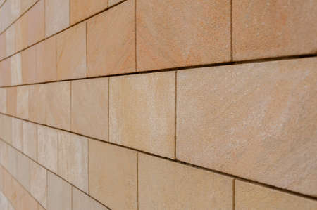 Modern sandstone facade cladding. Brown wall tiles imitating brickwork. Modern finishing material. Close-up of exterior facade decoration. Effective wall cladding systemの写真素材