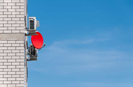 Satellite Dish or radio antennas against blue sky. Satellite dish for watching television are located on the building facade. Wireless technologyの写真素材