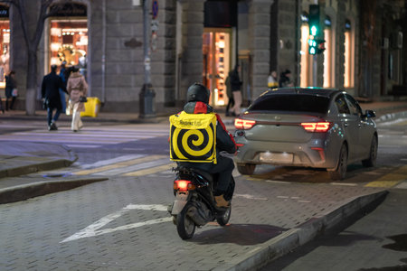 Krasnodar, Russia - January 03 2022: Yandex food delivery boy on scooter with isothermal food caseのeditorial素材