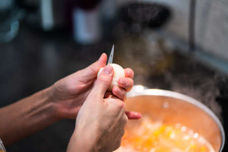 Womans hands cut an onion with a knife in half.の写真素材