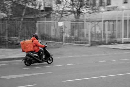 Food delivery boy on scooter with isothermal food caseの写真素材