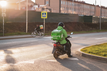 Krasnodar, Russia - January 06 2022: Food delivery boy on scooter with isothermal food caseのeditorial素材