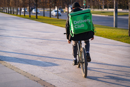 Krasnodar, Russia - January 7 2022: Food delivery boy ride on a bicycle with isothermal bagのeditorial素材