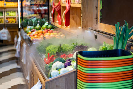 Local fresh market with fruits and vegetables on the shelves. Shopping baskets. Humidifier for greensの写真素材