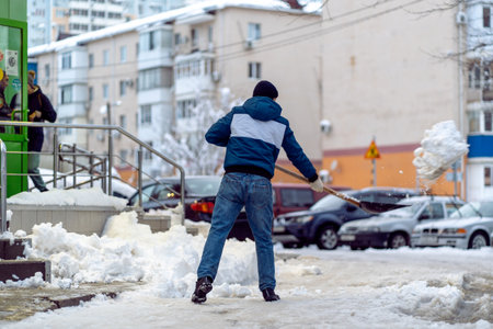 Krasnodar, Russia - January 24 2022: Man Removal Snow with a Shovel. Shoveling street from covered falling snowのeditorial素材