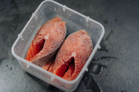 Top view of Fresh frozen raw red salmon fish. Frozen salmon steaks in a plastic box or containerの写真素材