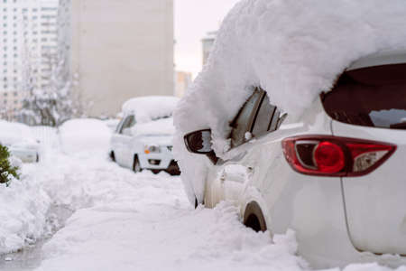 Snowfall in the city. Car covered in several inches of snow. Car almost totally buried