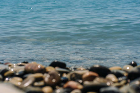 Bank of pebbles with the sea and beach in the background.の写真素材