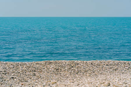 Bank of pebbles with the sea and beach in the background.の写真素材