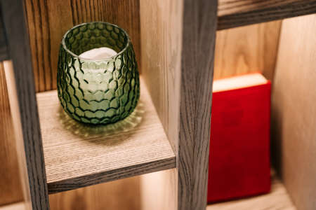 Red bound book and glass candlestick on the shelfの写真素材