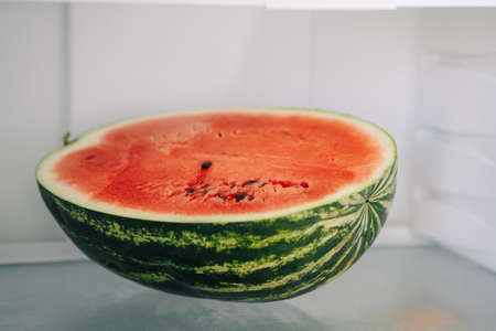 Half of fresh sliced watermelon on a shelf in the refrigerator.