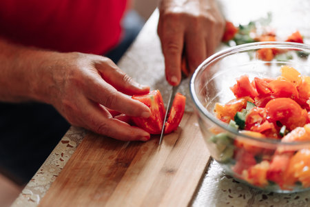 Close up on man slicing up small tomatoes. male hand cutting tomato on cutting board at home.の写真素材