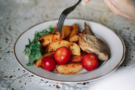 Picture of tasty baked fish with potatoes, greens and tomatoesの写真素材