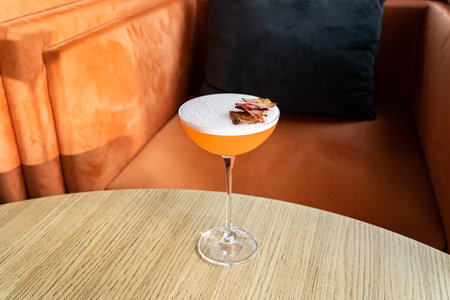Summer cocktail garnished with dried apple slices. Orange cold beverage on bar terrace.の写真素材