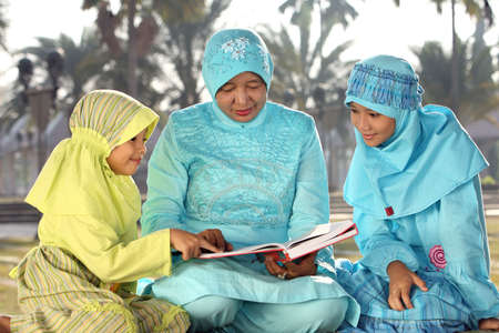 Muslim Mother and Kids Reading Qur'anの写真素材