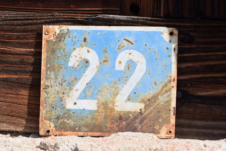 Metal plate with white number on a blue background applied on a background of old wood texture