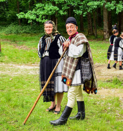 Romanian folk dancers in national linen pastoral costumes, sewn with traditional black motifs, men wear traditional round black cloth hats, and women wear black scarves with tasselsのeditorial素材
