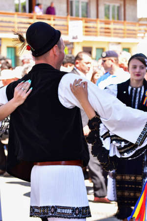 Romanian folk dancers in national linen pastoral costumes, sewn with traditional black motifs, men wear traditional round black cloth hats, and women wear black scarves with tasselsのeditorial素材
