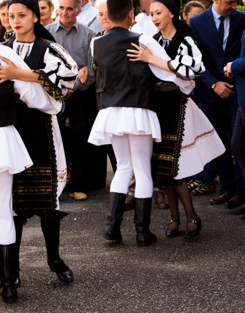 Romanian folk dancers in national linen pastoral costumes, sewn with traditional black motifs, men wear traditional round black cloth hats, and women wear black scarves with tasselsのeditorial素材