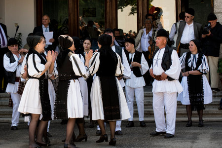 Romanian folk dancers in national linen pastoral costumes, sewn with traditional black motifs, men wear traditional round black cloth hats, and women wear black scarves with tasselsのeditorial素材