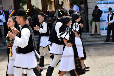 Romanian folk dancers in national linen pastoral costumes, sewn with traditional black motifs, men wear traditional round black cloth hats, and women wear black scarves with tasselsのeditorial素材