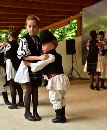 Romanian folk dancers in national linen pastoral costumes, sewn with traditional black motifs, men wear traditional round black cloth hats, and women wear black scarves with tasselsのeditorial素材