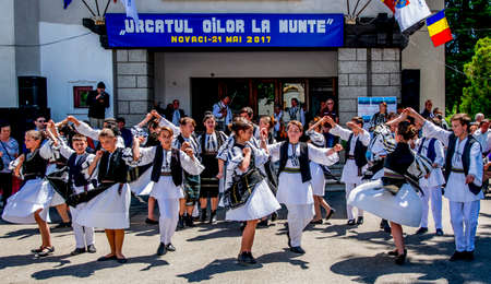 Romanian folk dancers in national linen pastoral costumes, sewn with traditional black motifs, men wear traditional round black cloth hats, and women wear black scarves with tasselsのeditorial素材