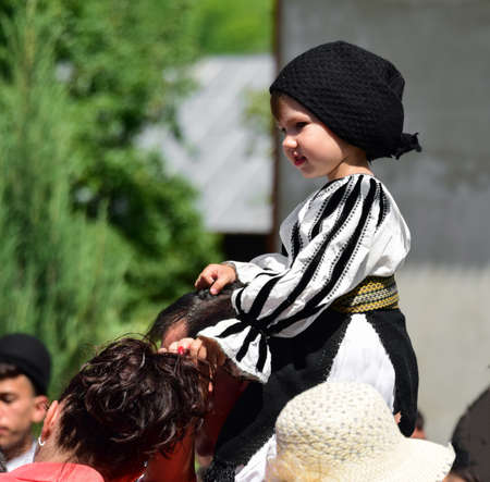 girl from Novaci Romania dressed in a national shepherd's costume made of linen fabric with traditional black motifs and wearing a black scarf with tassels on her headのeditorial素材