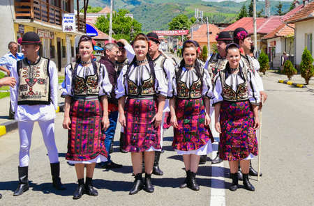 Romanian folk dancers in national linen pastoral costumes, sewn with traditional black motifs, men wear traditional round black cloth hats, and women wear black scarves with tasselsのeditorial素材