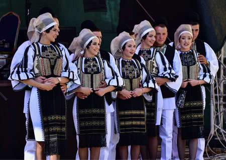 girls and boys from the Sibiu meadow dressed in pastoral costumes men wear round black cloth hats, a shirt with a skirt, trousers, a wide leather belt, a chest and the girls wear a white scarf, a shirのeditorial素材