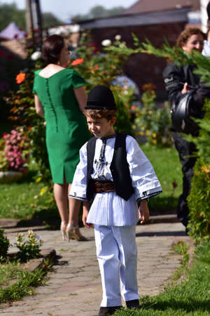 boy from Sibiu Romania meadow dressed in national linen shepherd costume, sewn with traditional black motifs, consisting of a shirt with skirt, pants, a wide leather belt, chest and wearing a black paのeditorial素材